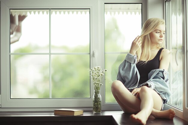 Window sitting young adult girl at home