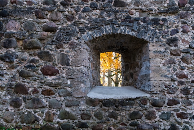 秋の風景の中の石の壁のウィンドウ