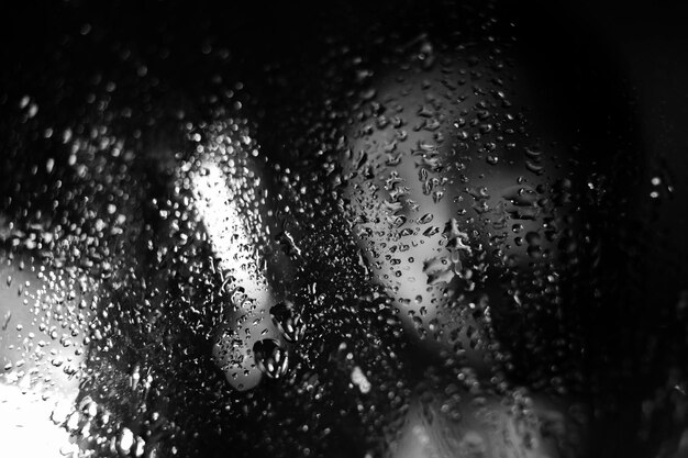 a window with raindrops on it and a light in the background