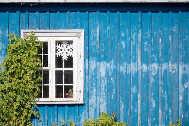 a window with white trim is on a blue house.