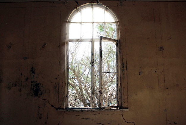 Window without glass and dirty walls in an abandoned house