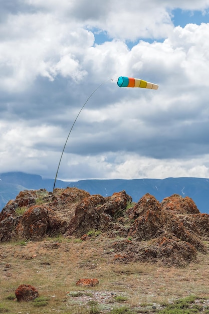 Windsok in de bergen windaanduiding tegen de blauwe bergen windmouw die op een blauwe bewolkte hemel vliegt