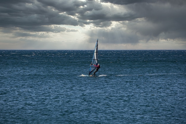 Windsurfer pratica con la sua tavola da surf nel mare adriatico