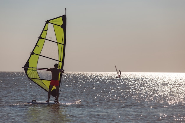 Windsurfers in de zee tijdens zonsondergang, actieve levensstijl.