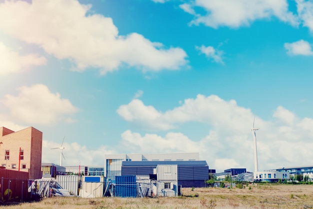 Windturbine midden op industrieterrein als bron van hernieuwbare energie op blauwe hemelachtergrond