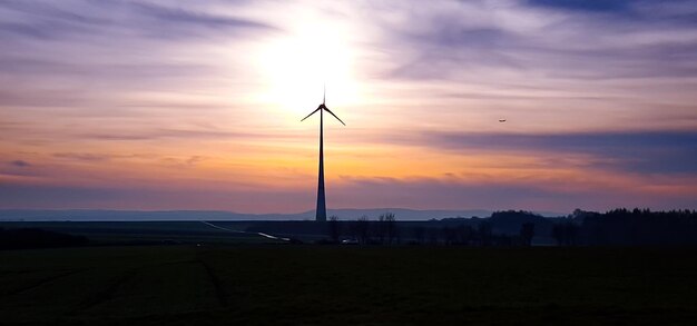 Foto windturbine op landschap tegen bewolkte lucht tijdens zonsondergang