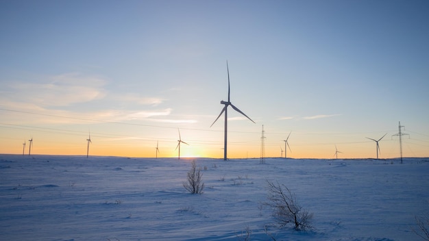 Windturbines te midden van een besneeuwd landschap tijdens zonsondergang symboliseren hernieuwbare energie en duurzaamheid