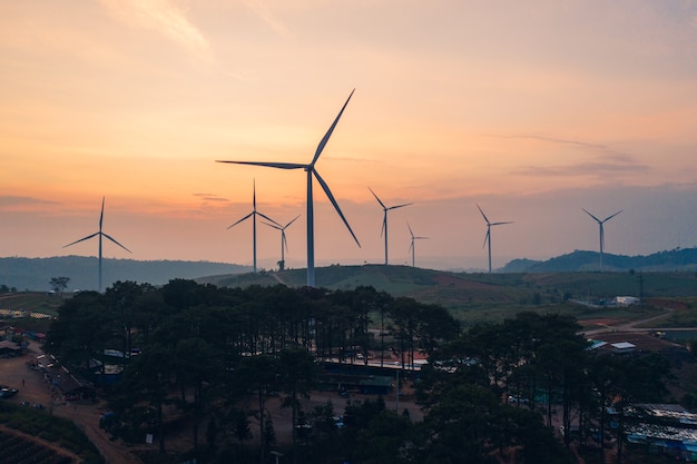 Windturbines van alternatieve energie met schoon en hernieuwbaar op heuvel in landbouwvelden 's avonds