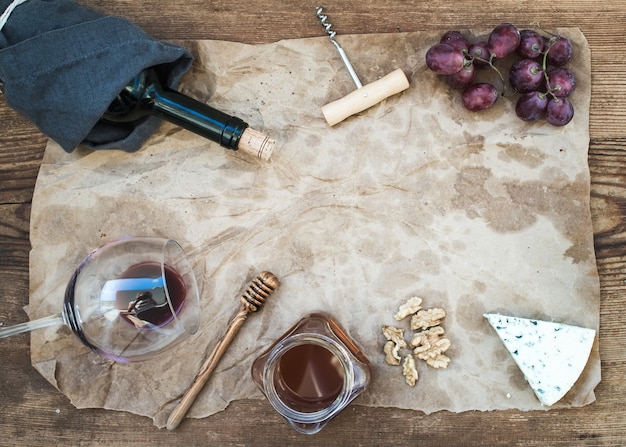 素朴な木製のテーブルの上の油性クラフト紙にワインと前菜を設定