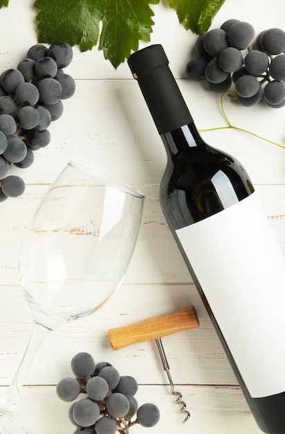 写真 ワインボトルとワイングラスで,白い木製の背景にブドウが描かれています. 垂直写真トップビュー