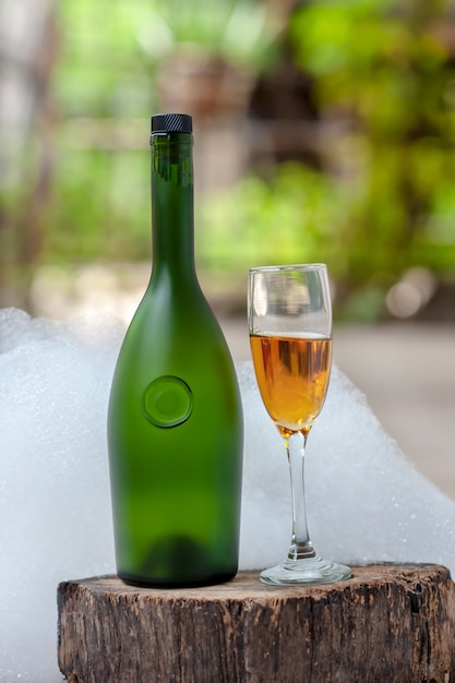 ワインのボトルと白い泡の背景を持つシャンパングラス