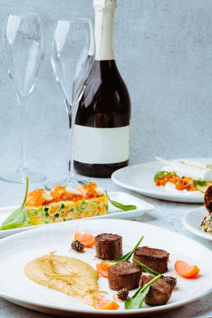 Photo wine bottle and full dinner course plates with meat salads and icecream