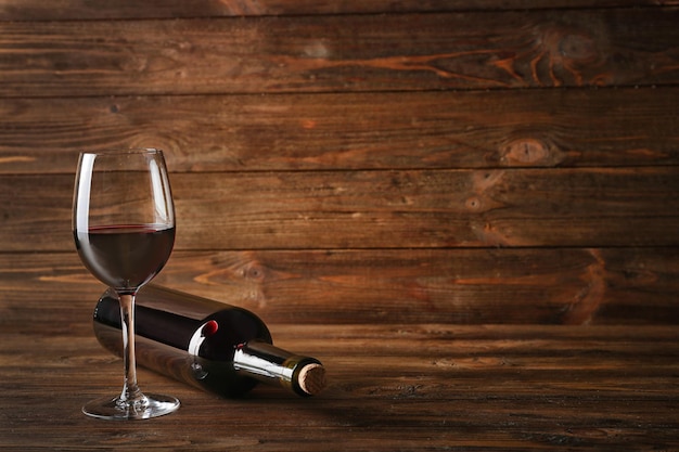 Foto bottiglia di vino e vetro su sfondo di legno