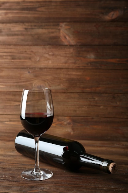 Бутылка вина и бокал на деревянном фоне