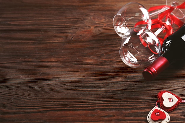 Wine bottle and glasses with handmade hearts on wooden background