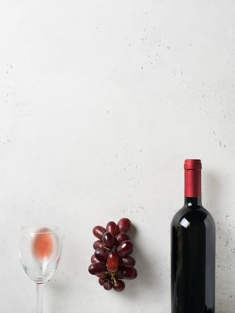 Wine bottle, grape and glasses on white stone  background, copy space, top view