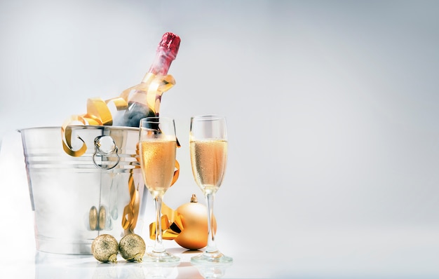 Wine bottle on ice bucket and a pair of glasses with christmas decoration