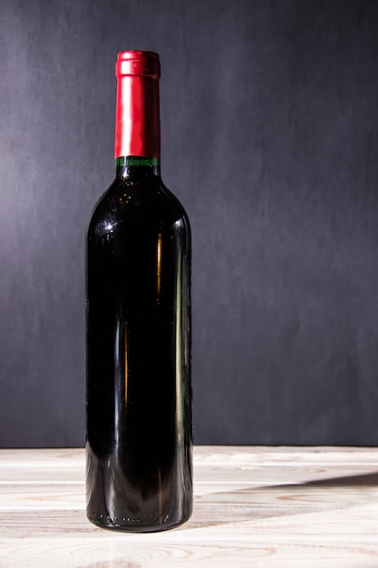 Photo wine bottle standing on a wooden table on dark