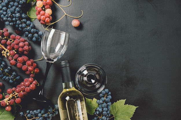 wine bottle, two wine glasses, fresh grapes and leaves 