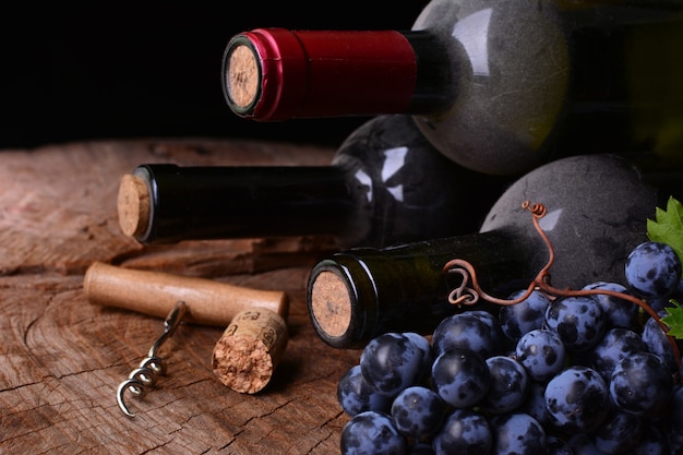 Wine bottles, cork and grape on wooden surface