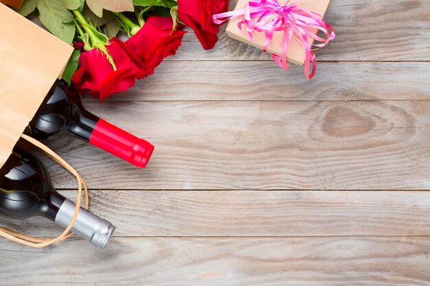 Wine bottles and rose flowers on wooden table