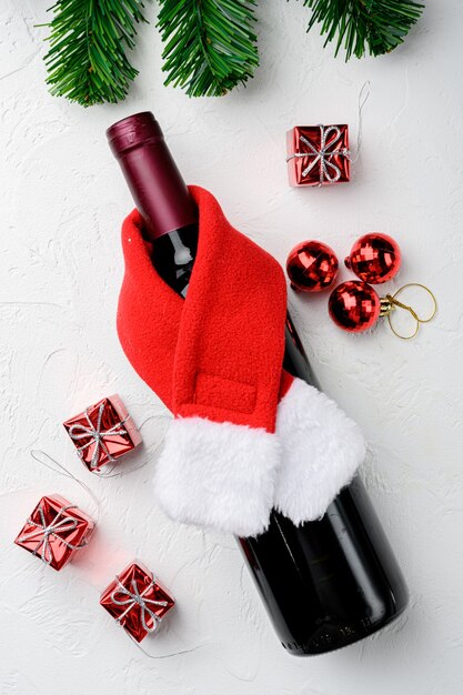 Wine bottles with Santa red hat set, on white stone table background, top view flat lay