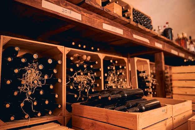 Wine cellar with bottles of alcoholic drink in wooden boxes and shelves with vintage year labels