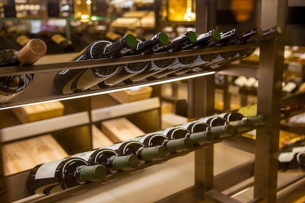 Wine cellar with elite drinks on shelves wine bottles in the shop close up