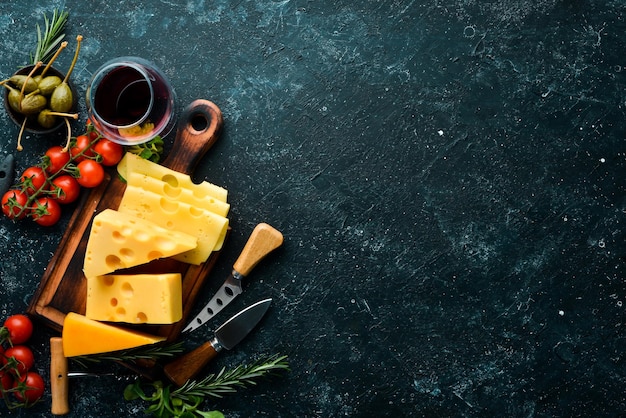 Wine cheese and snacks on a black stone background Assorted cheese Top view Free space for your text