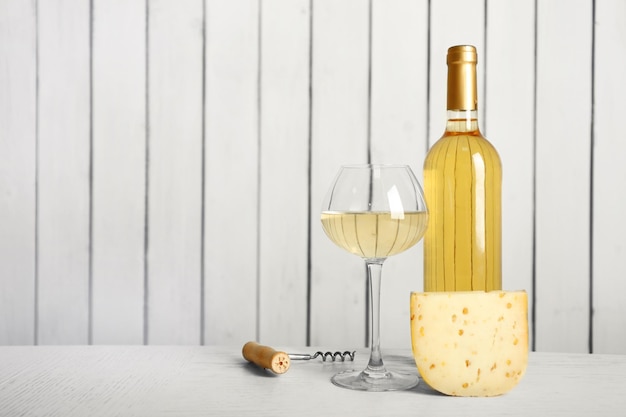 Photo wine and cheese on wooden wall background