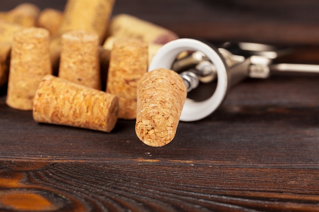 Wine corks with corkscrew on wooden table