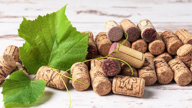 Wine corks with grape leaf over wooden background Grape and wine concept