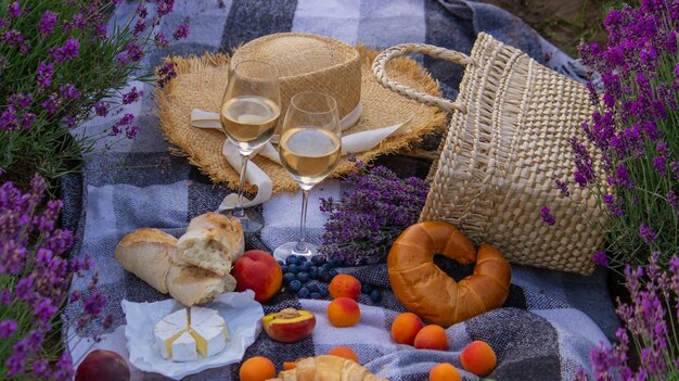 Wine fruits berries cheese glasses picnic in lavender field Selective focus