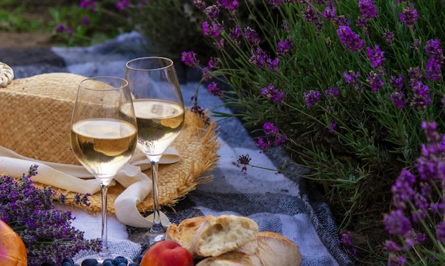 Wine fruits berries cheese glasses picnic in lavender field Selective focus