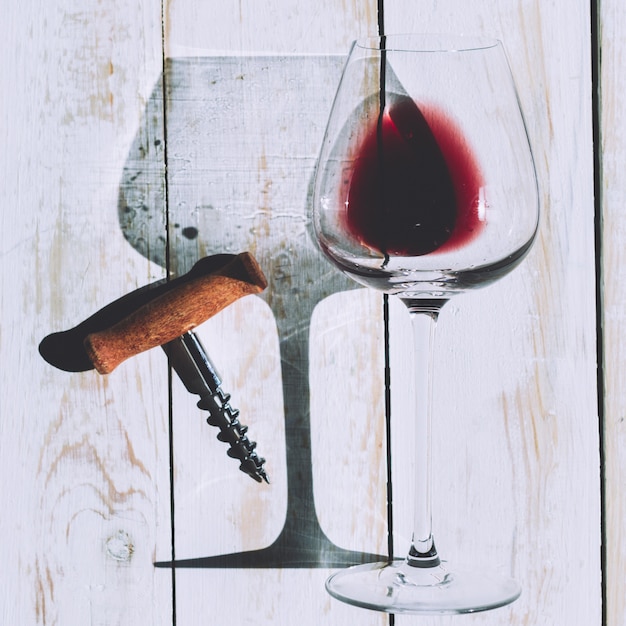 Wine glass, cork and corkscrew over wooden table