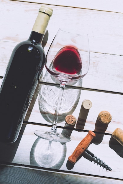 Wine glass, cork and corkscrew over wooden table