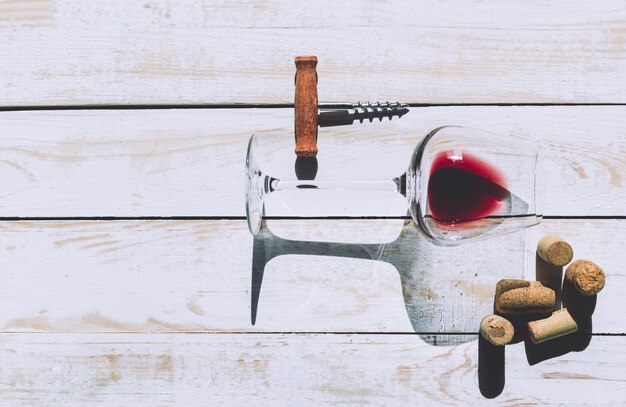 Foto bicchiere da vino, sughero e cavatappi sul tavolo di legno