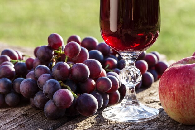 Wine in a glass and grapes on a wooden table.