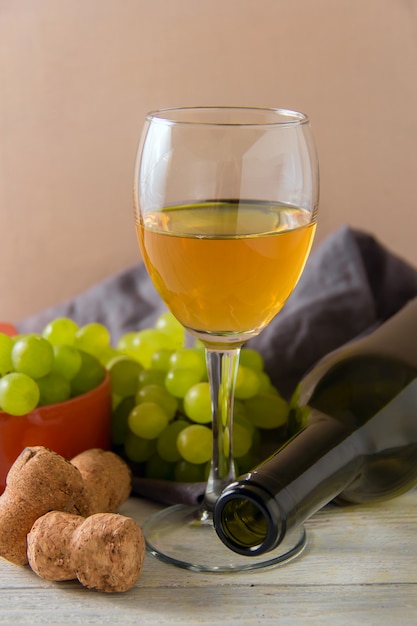 Wine glass, green grapes on plate on table.