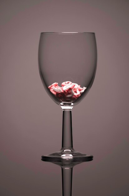 Photo a wine glass half filled with a heart shape candies