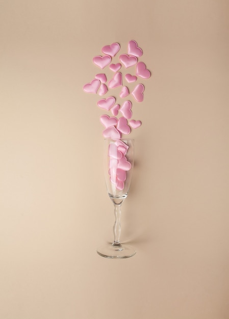 Wine glass with pink hearts on a beige background