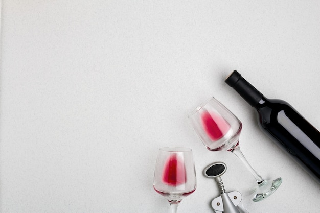 Wine glasses and corkscrew over white background top view