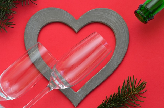 Wine glasses, heart and spruce branches on a red background