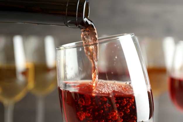 Wine is poured from bottle into a glass, close up and selective focus