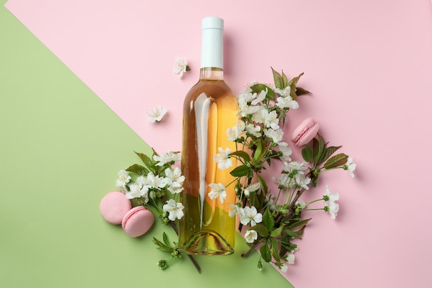 Wine, macaroons and flowers on two tone background