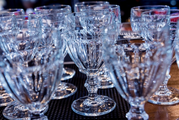 Wine and martini glasses in shelf above a bar rack in restaurant. Empty clean glasses in bar.