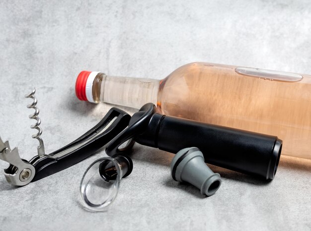 Photo wine opener accessories toolsrose bottle and brie camembert cheese isolated gray tiles backgroundg