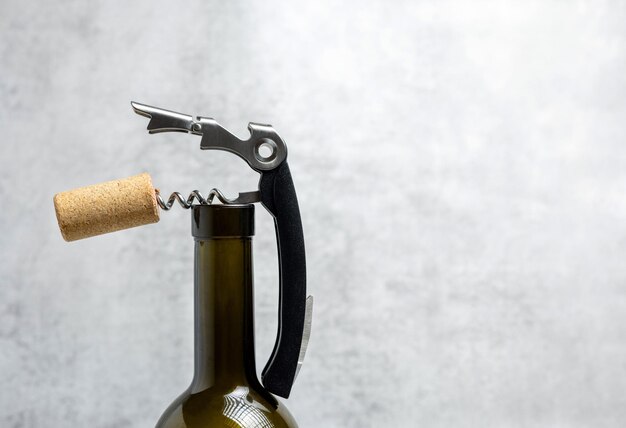 Photo wine opener accessories toolsrose bottle and brie camembert cheese isolated gray tiles backgroundg