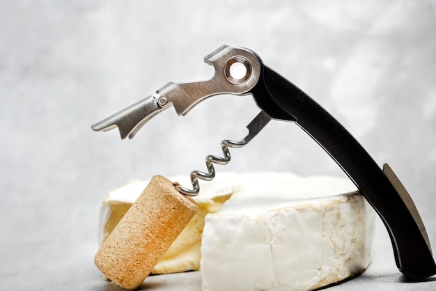 Foto accessori apribottiglie bottiglia toolsrose e formaggio camembert brie isolato sfondo grigio piastrelle