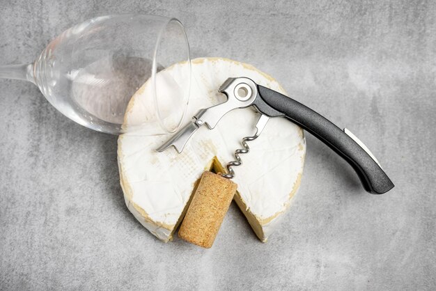 Photo wine opener accessories toolsrose bottle and brie camembert cheese isolated gray tiles backgroundg